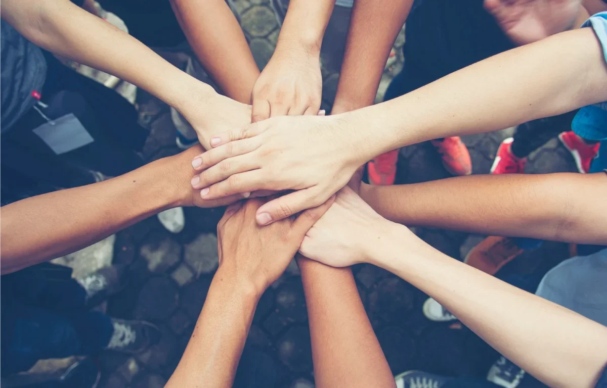 Team members with their hands stacked together in a circle, showcasing unity and teamwork in providing exceptional junk removal services.